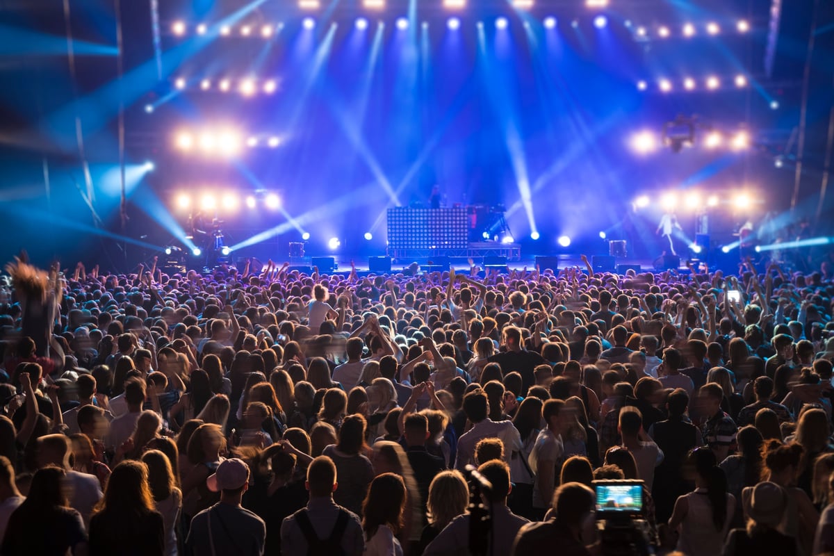 Back view of a crowd at a music festival under vibrant blue stage lights